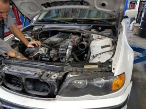 technicians working under the hood of a white sports car